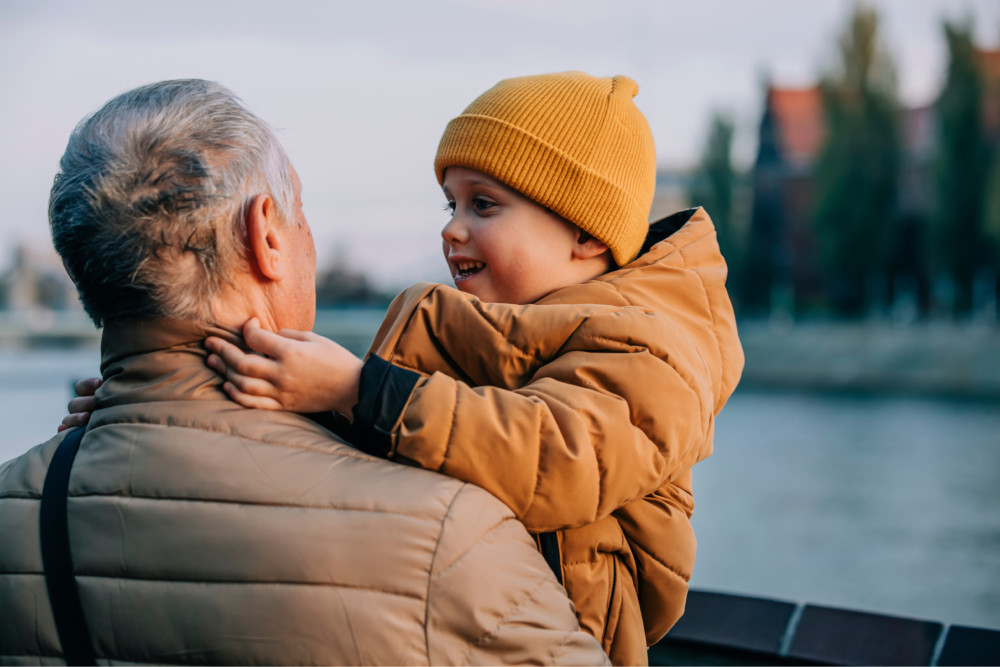 A man holding a child near a body of water